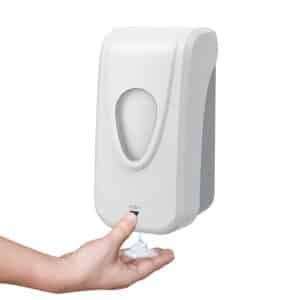 Wall-mounted white manual soap dispenser in use, dispensing foam or liquid into a user’s hand.