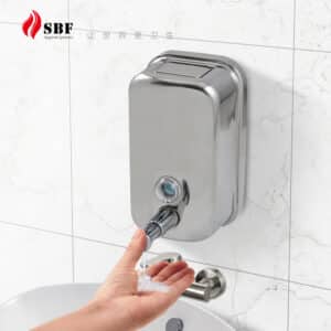 Wall-mounted stainless steel manual soap dispenser in use, showing liquid being dispensed with hand press; ideal for commercial restroom hygiene.