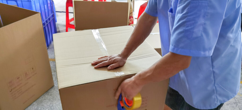 AOLQ worker sealing cartons for secure packaging and safe delivery of public hygiene products worldwide